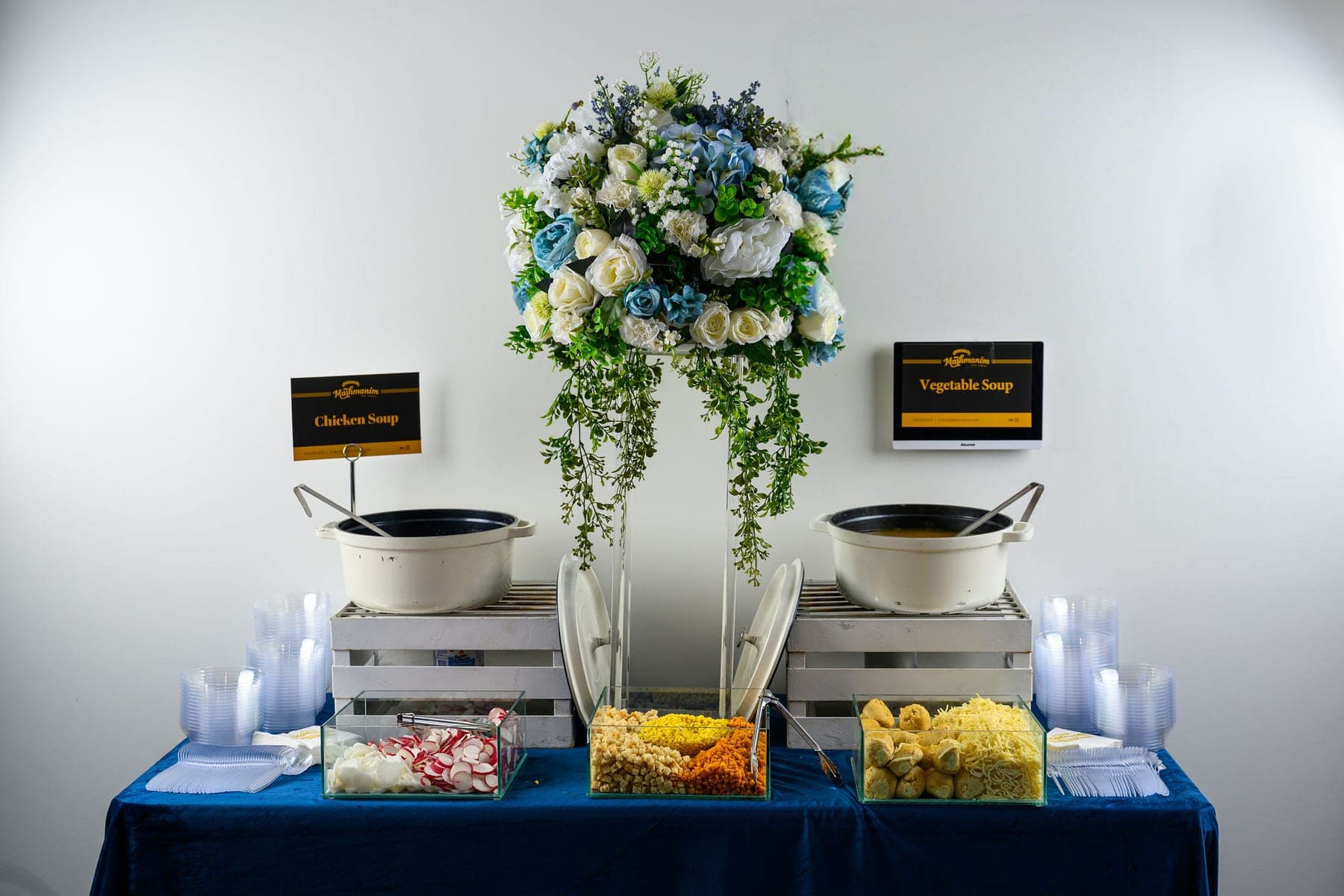 The soup station: two white pots on crates either side of a tall floral arrangement, garnishes in glass dishes in front