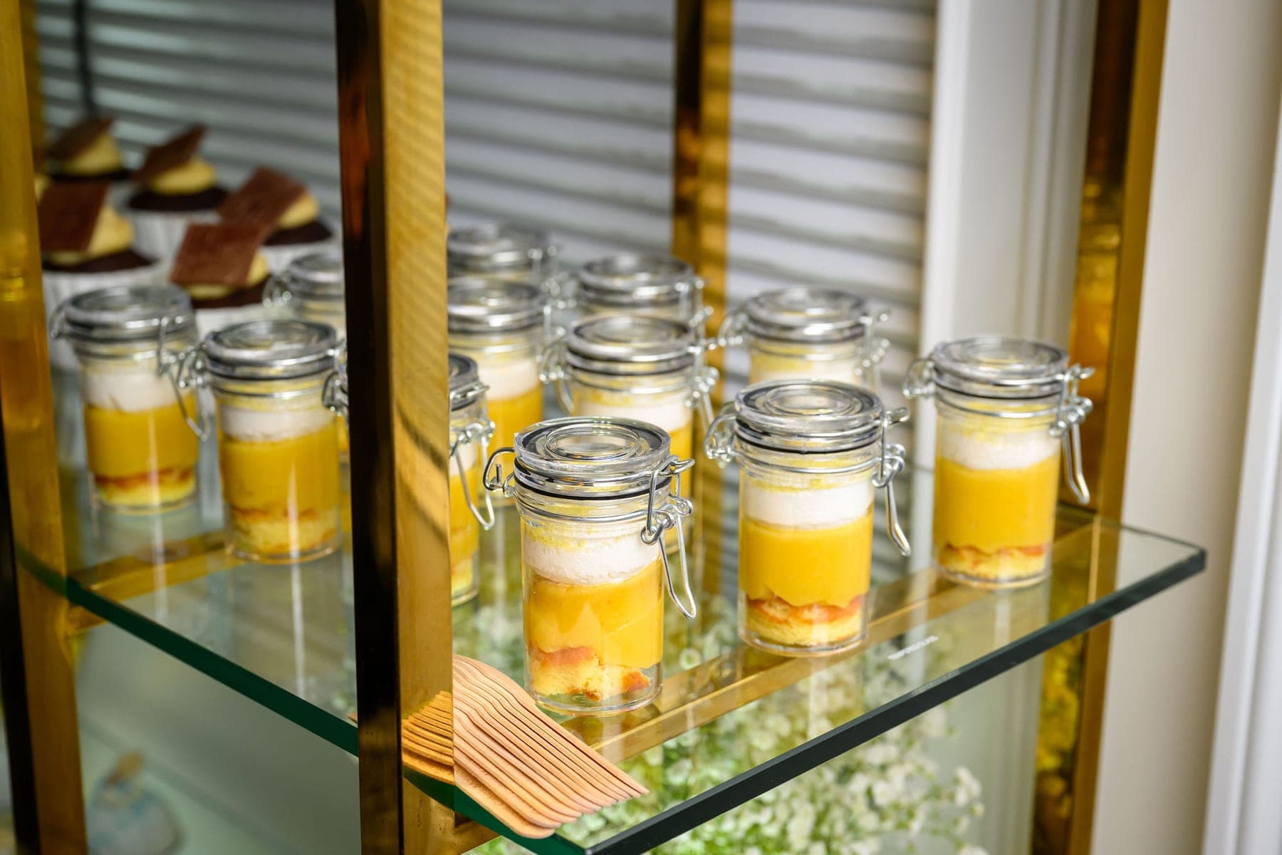 Jars of mousse in rows on a glass and gold shelf