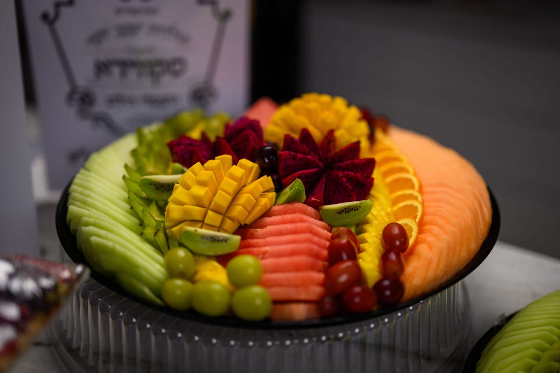 A carved fruit platter, melon and mango fanned around the rim